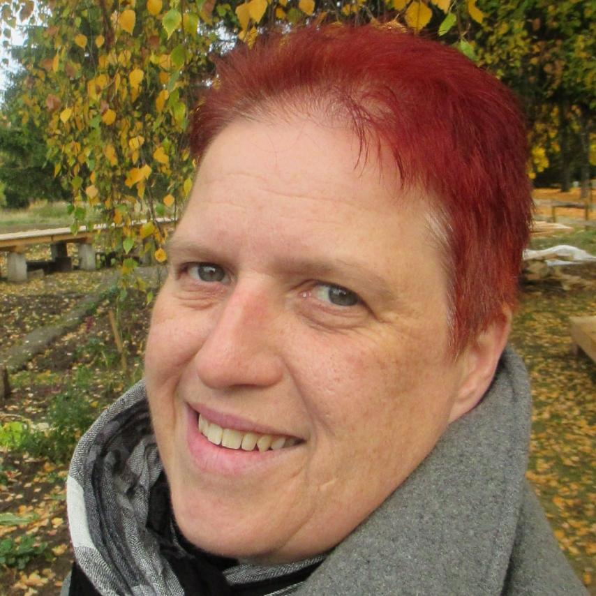 Eine Frau mit kurzen roten Haaren lächelt in die Kamera
